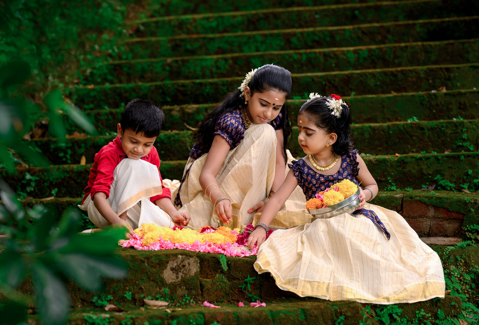Children in traditional Kerala dress laying a flower carpet for Onam