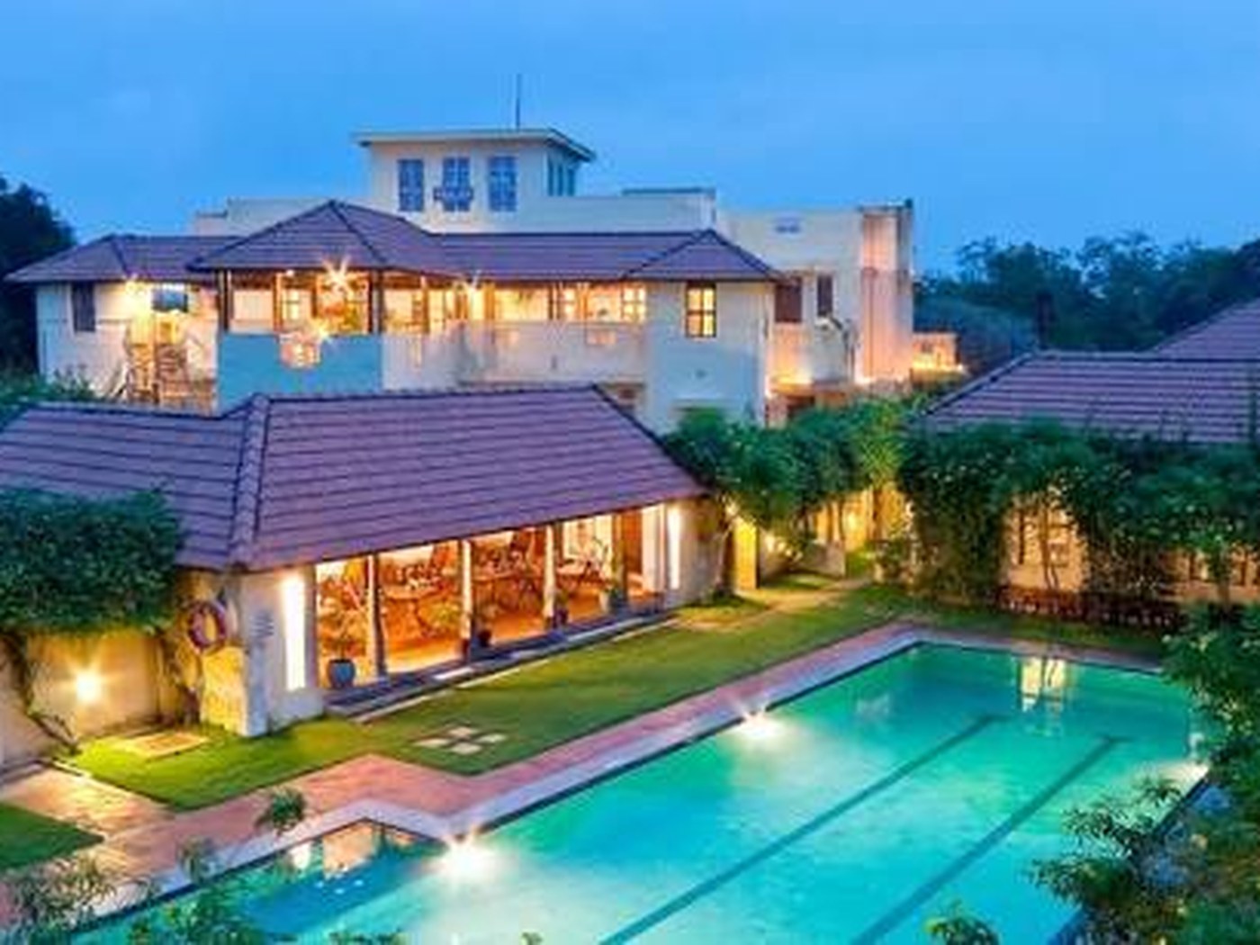 Lit mansion and pool at dusk at CGH Visalam in Karaikudi