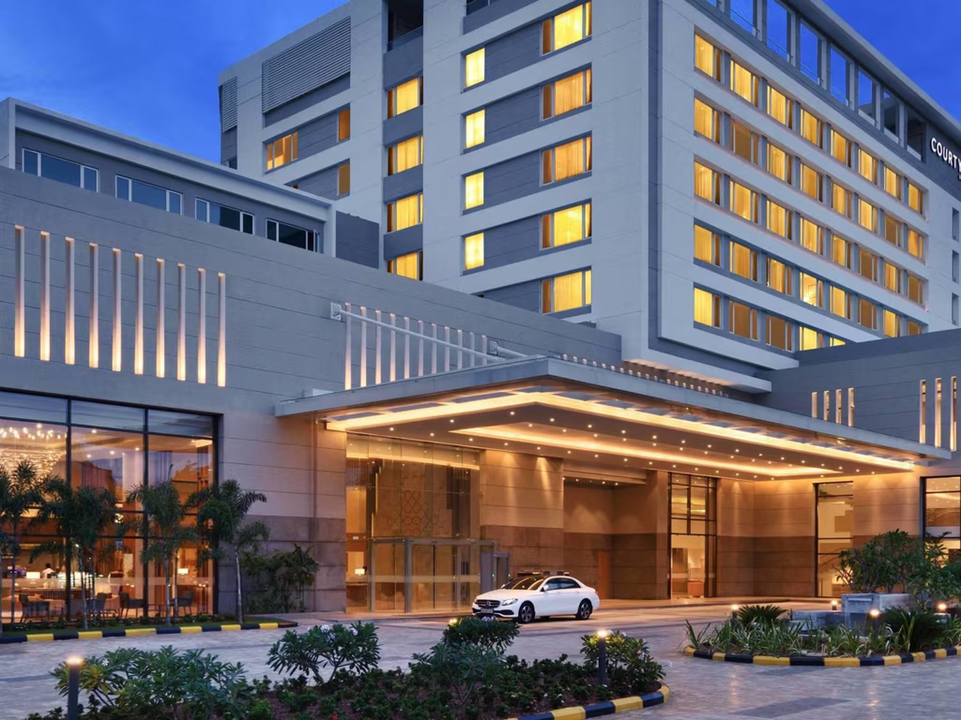 Lit porte-cochere and facade of Marriott Madurai at dusk