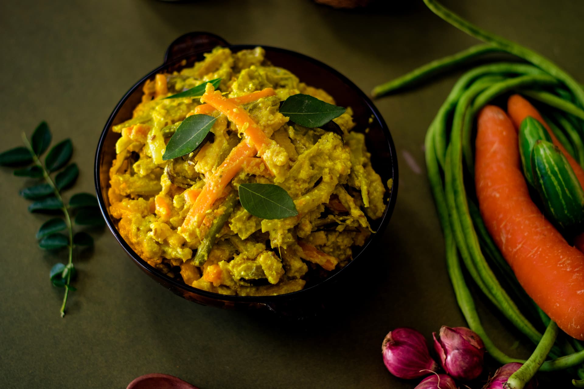 A vegetable dish served in a bowl beside fresh vegetables