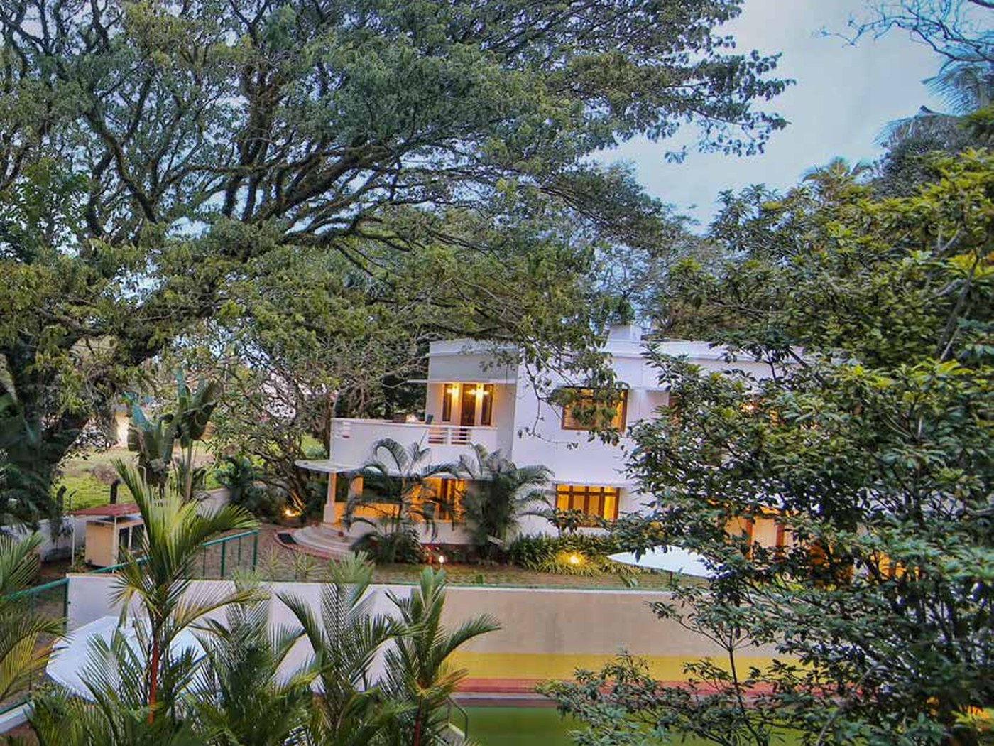 Beach Gate Bungalows lit at dusk beside the pool and gardens in Fort Kochi