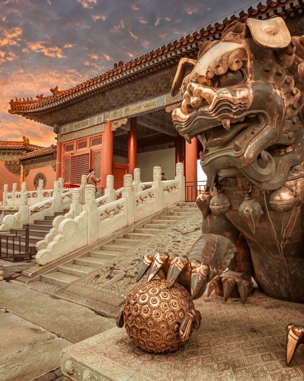 A bronze guardian lion at the gates of the Forbidden City in Beijing at sunset