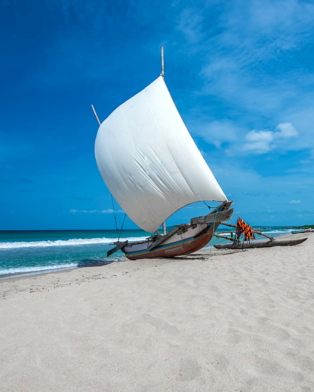 A traditional sailing outrigger on a white sand beach in Sri Lanka