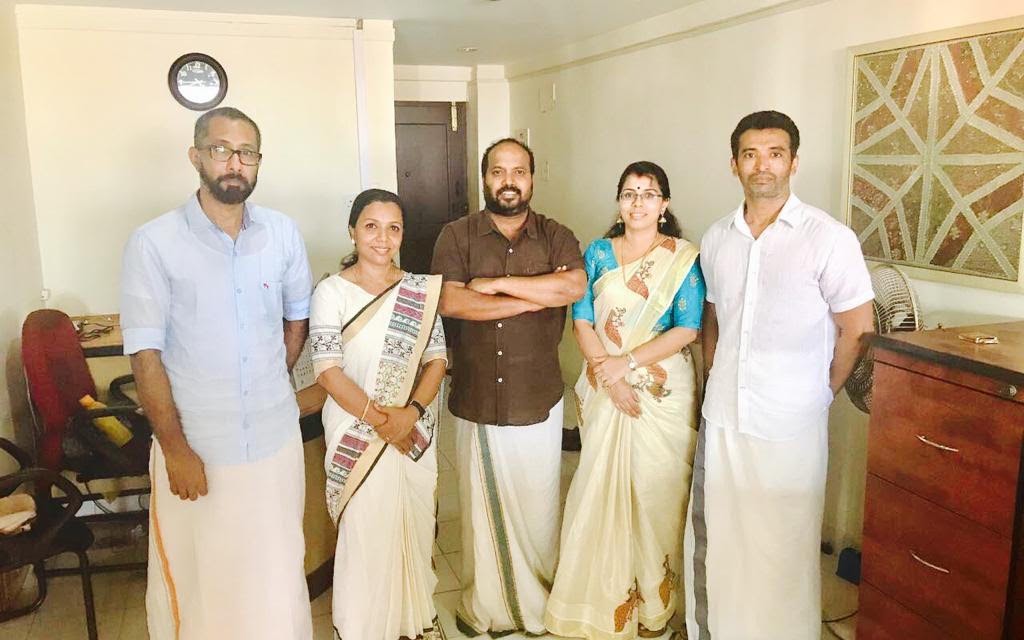 Five members of the Kerala Travel Centre team standing together in traditional Kerala dress at the Cochin office