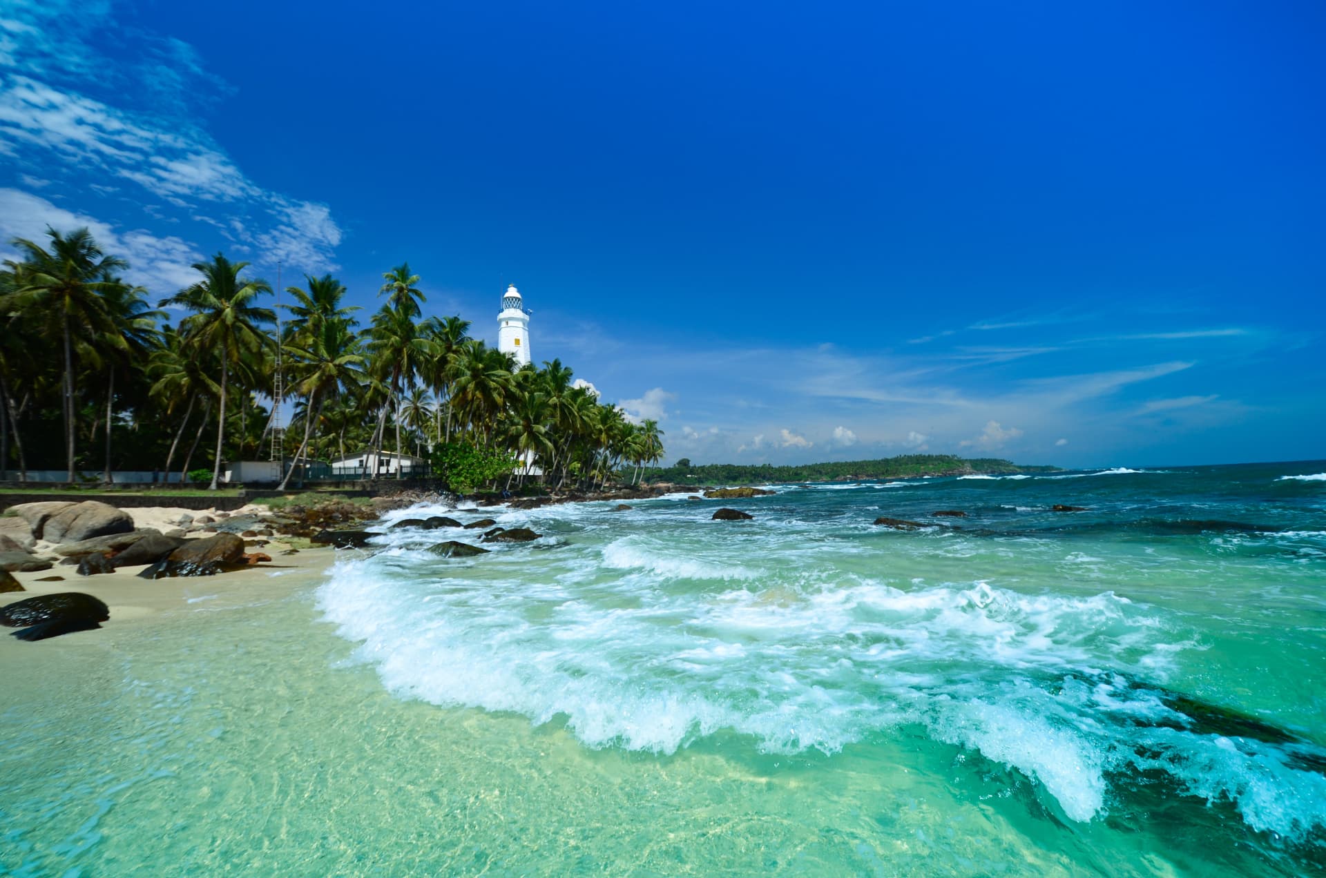 A white lighthouse and palm-fringed beach on the south coast of Sri Lanka