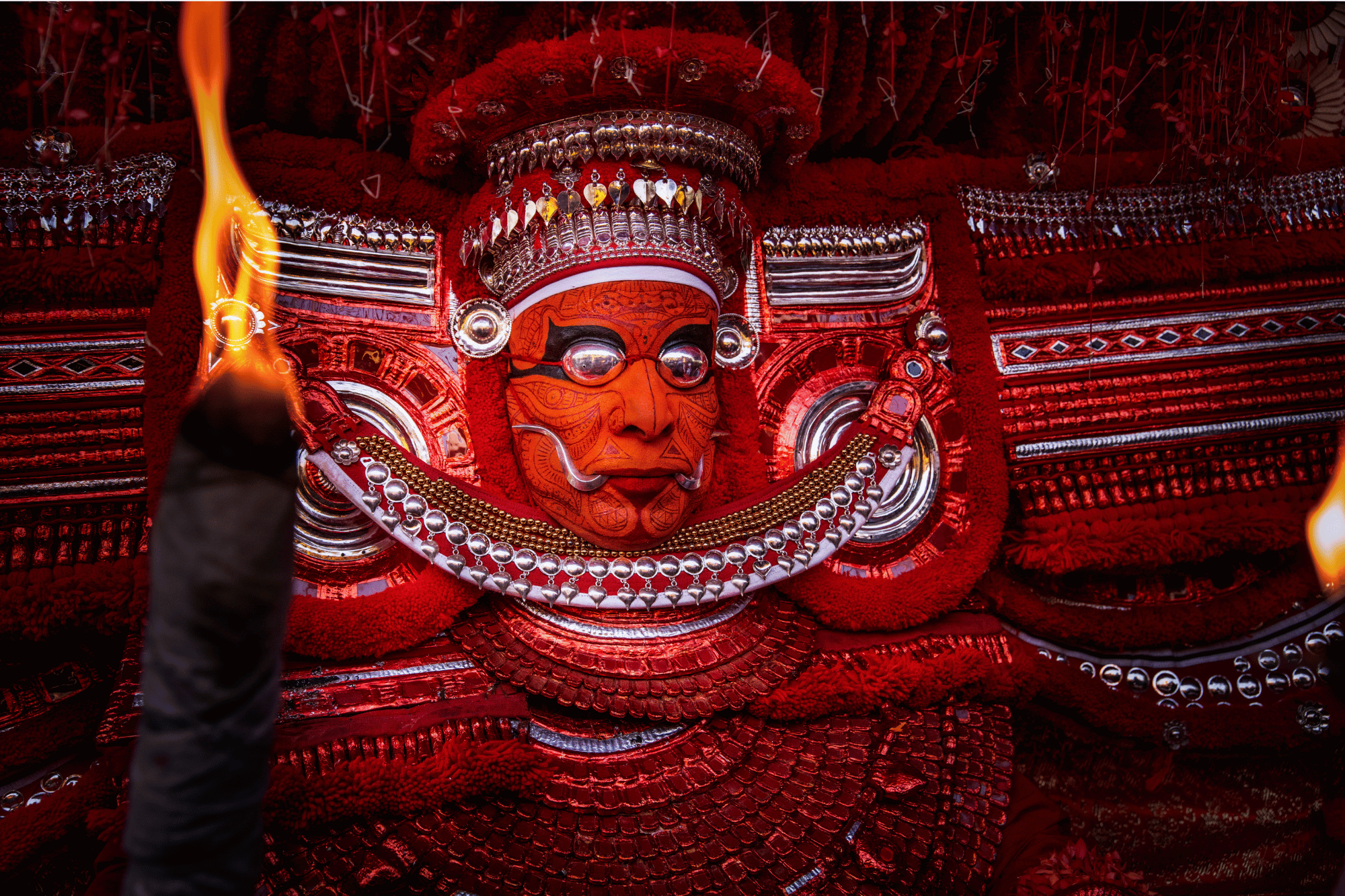 A Theyyam performer wearing red ceremonial make-up and costume