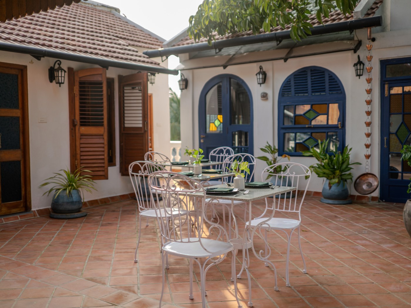 Courtyard with blue shutters and cafe tables at Résidence de l'Evêché