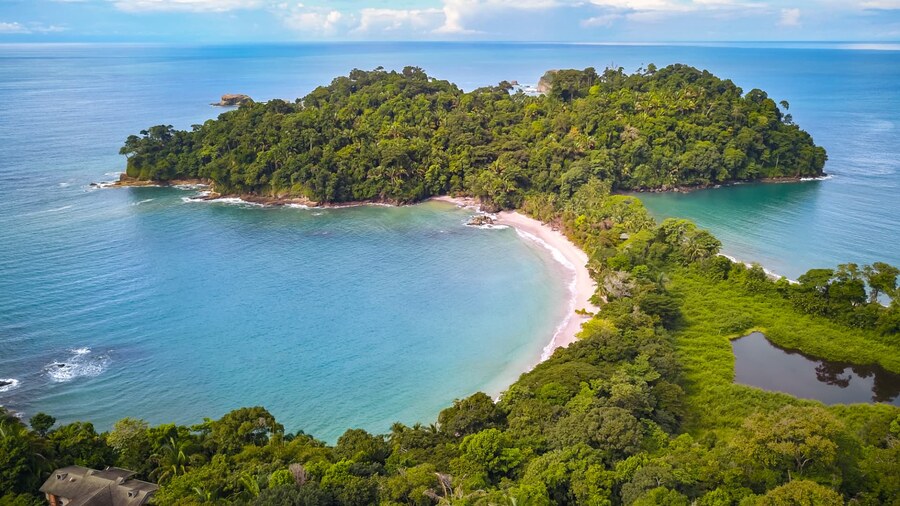 An aerial view of the rainforest headland and turquoise bay at Manuel Antonio