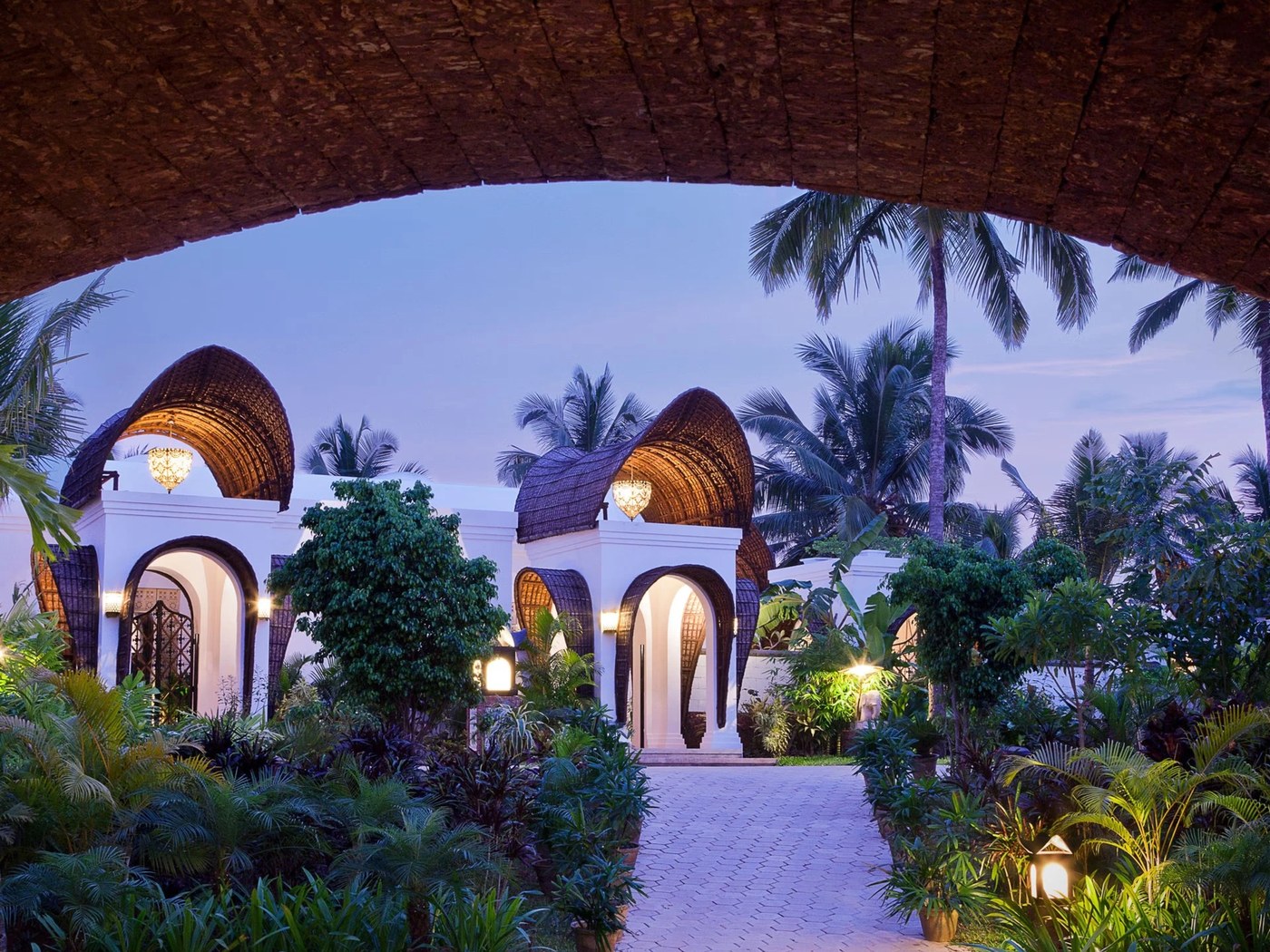 Thatched arched pavilions lit at dusk at Vivanta by Taj Bekal