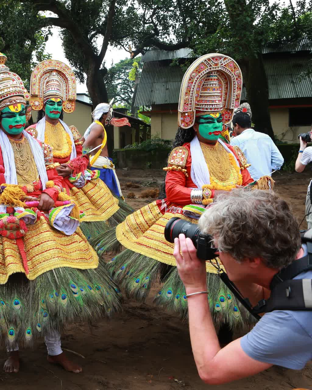 Kathakali performers in full costume being photographed by a guest on a Kerala cultural tour